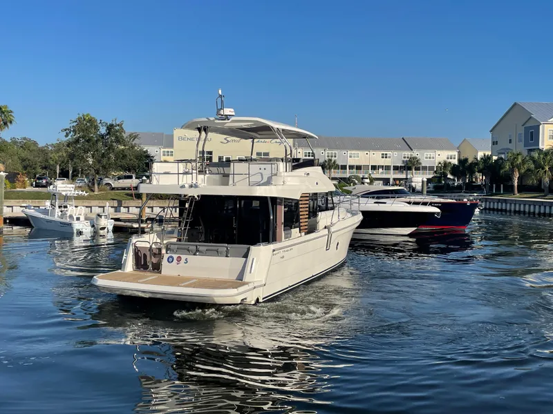 Slide: The Image of 2025 Beneteau Swift Trawler 48 cruising in a marina on a sunny day. - 11