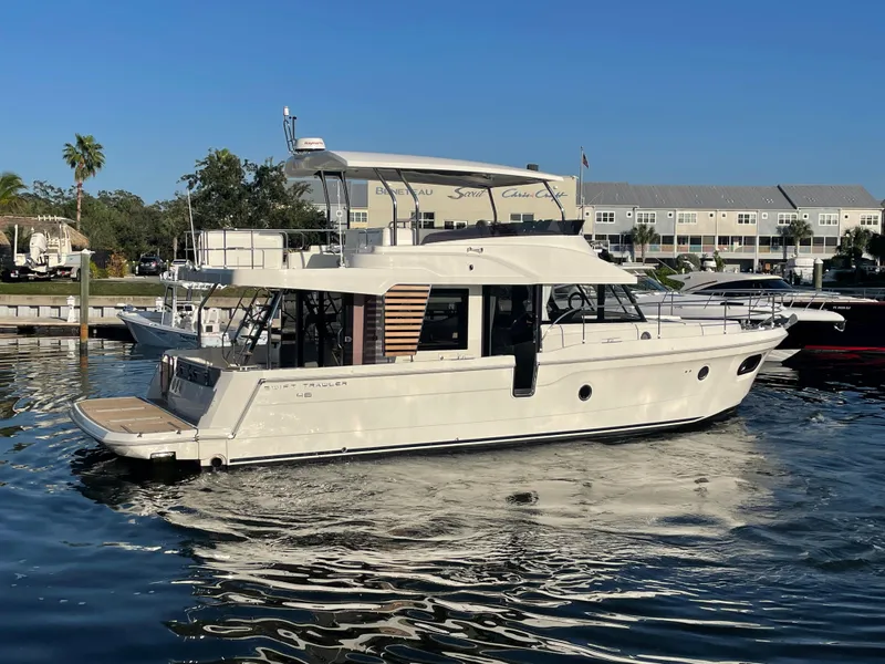 Slide: The Image of 2025 Beneteau Swift Trawler 48 docked in a marina on a sunny day. - 13