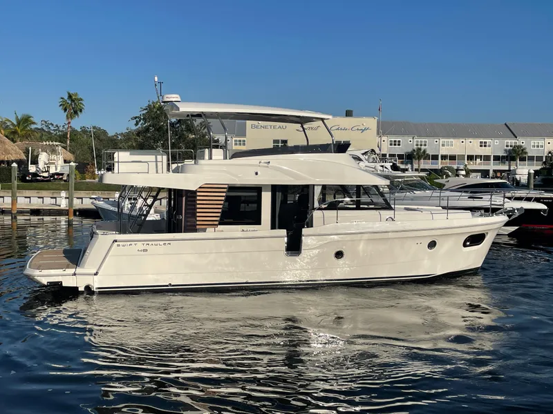 Slide: The Image of 2025 Beneteau Swift Trawler 48 docked in a marina on a sunny day. - 14