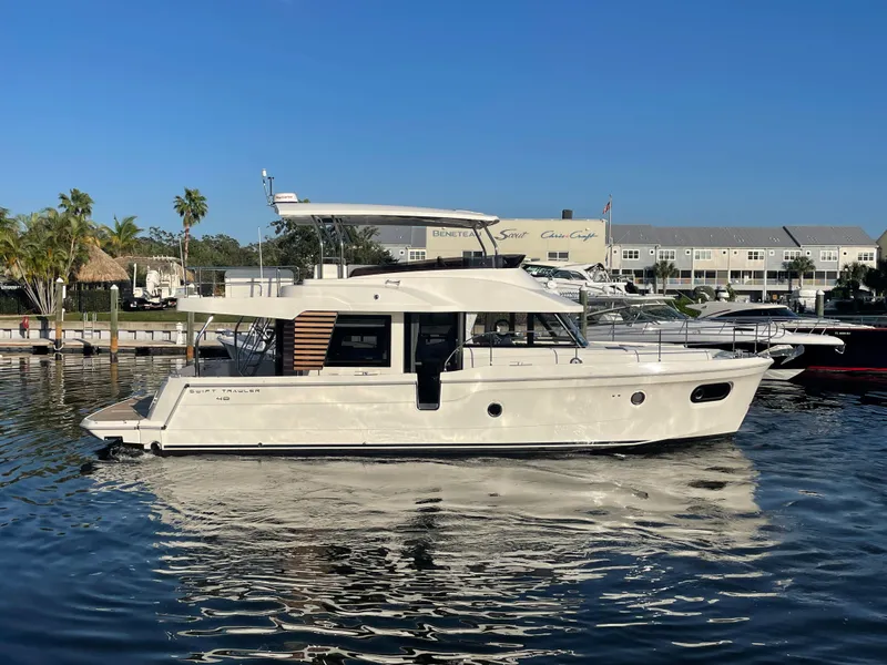 Slide: The Image of 2025 Beneteau Swift Trawler 48 docked at a marina on a sunny day. - 15