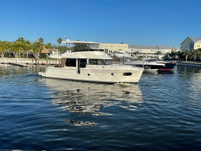 Slide: The Image of 2025 Beneteau Swift Trawler 48 cruising in a marina on a sunny day. - 16
