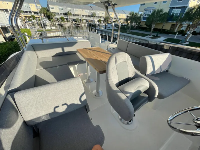 Slide: The Image of 2025 Beneteau Swift Trawler 48 interior with grey seating and wooden table. - 18