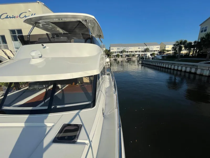 Slide: The Image of 2025 Beneteau Swift Trawler 48 docked at a marina on a sunny day. - 27