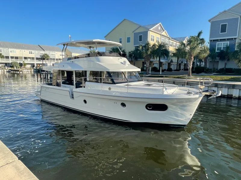 Slide: The Image of 2025 Beneteau Swift Trawler 48 docked in a marina with waterfront homes. - 3