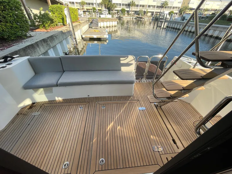Slide: The Image of 2025 Beneteau Swift Trawler 48 aft deck with teak flooring and cushioned seating. - 30