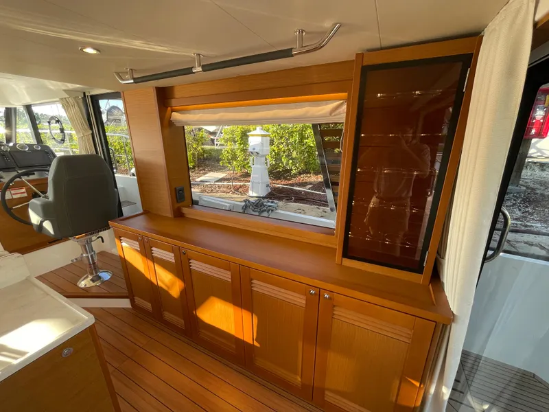 Slide: The Image of Interior of 2025 Beneteau Swift Trawler 48 with wooden cabinetry and large window. - 35