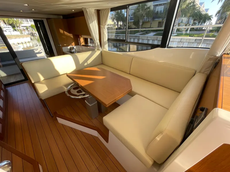 Slide: The Image of Interior of 2025 Beneteau Swift Trawler 48 with beige seating and wooden table. - 36