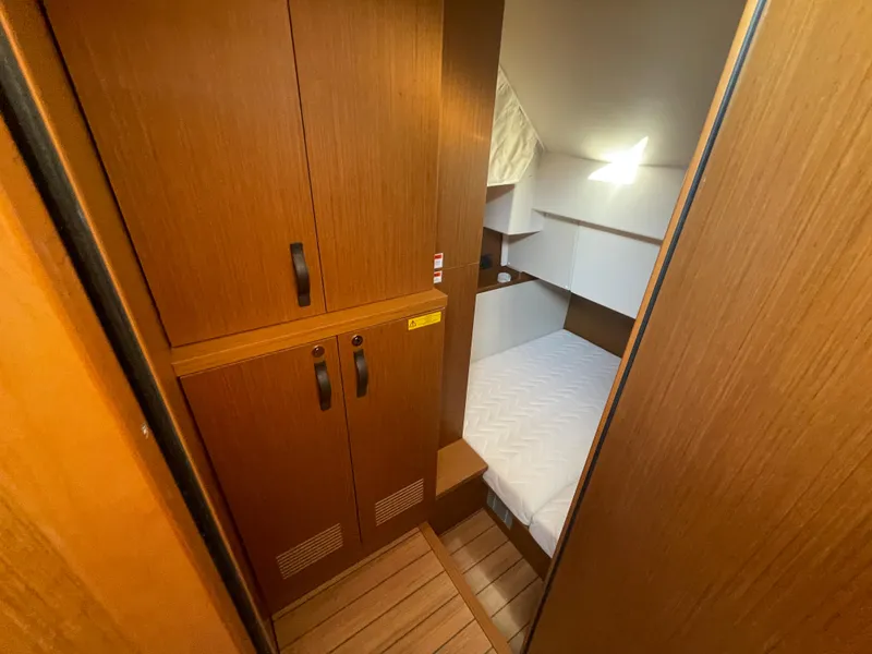 Slide: The Image of 2025 Beneteau Swift Trawler 48 cabin with wooden cabinetry and cozy bed. - 43