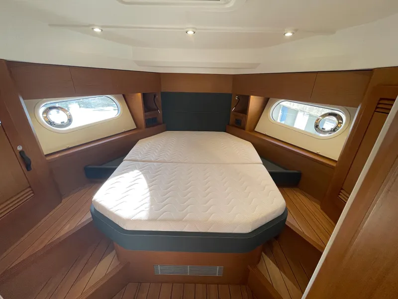 Slide: The Image of 2025 Beneteau Swift Trawler 48 cabin with double bed and wooden interior. - 46