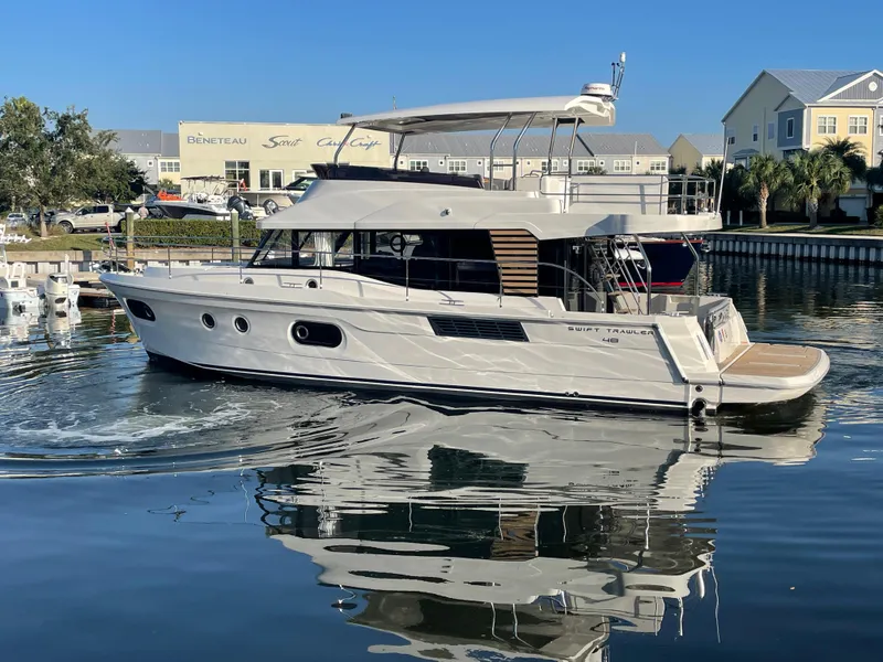 Slide: The Image of 2025 Beneteau Swift Trawler 48 on calm water near marina. - 7