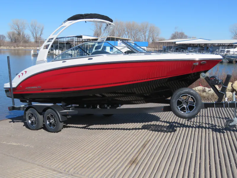 Slide: The Image of 2024 Chaparral 23 Surf boat on a trailer at a lakeside dock. - 0