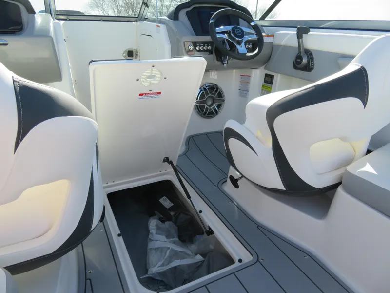 Slide: The Image of 2024 Chaparral 23 Surf boat interior with open storage compartment and helm. - 23