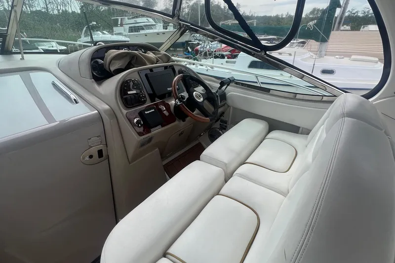 Slide: The Image of 2002 Sea Ray 300 Sundancer cockpit with white leather seats and modern dashboard. - 11
