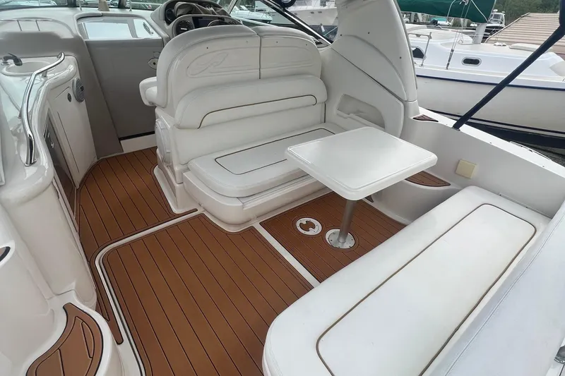 Slide: The Image of Interior of 2002 Sea Ray 300 Sundancer with white seating and wooden flooring. - 14