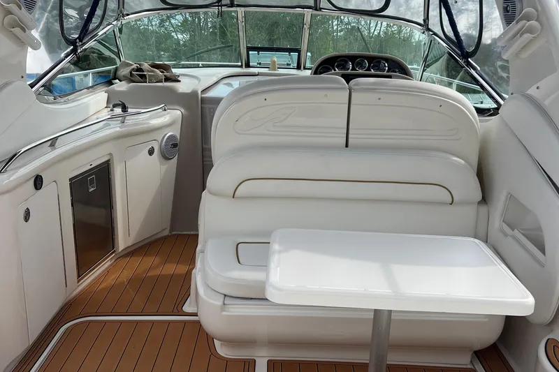 Slide: The Image of Interior of 2002 Sea Ray 300 Sundancer boat with white seating and wooden flooring. - 15