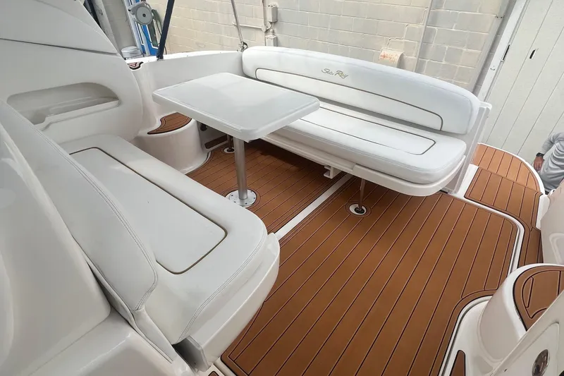Slide: The Image of 2002 Sea Ray 300 Sundancer boat interior with white seating and wooden flooring. - 16