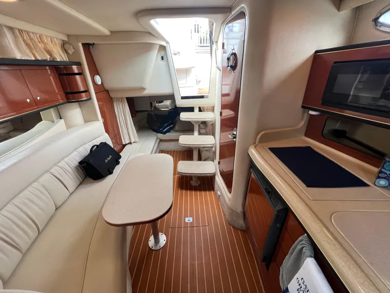 Slide: The Image of Interior of 2002 Sea Ray 300 Sundancer yacht with seating, table, and kitchenette. - 18