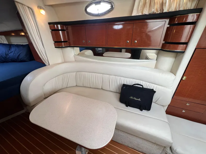 Slide: The Image of 2002 Sea Ray 300 Sundancer interior with white leather seating and wooden cabinets. - 19