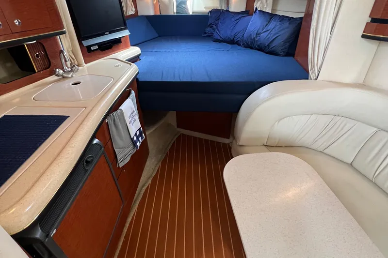 Slide: The Image of 2002 Sea Ray 300 Sundancer interior with kitchenette, seating area, and bed. - 21