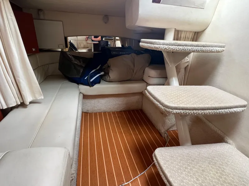 Slide: The Image of Interior cabin of a 2002 Sea Ray 300 Sundancer boat with beige seating and wooden flooring. - 23