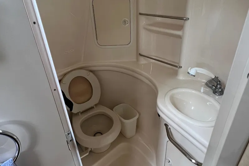 Slide: The Image of Compact bathroom in 2002 Sea Ray 300 Sundancer boat with toilet, sink, and storage shelves. - 24