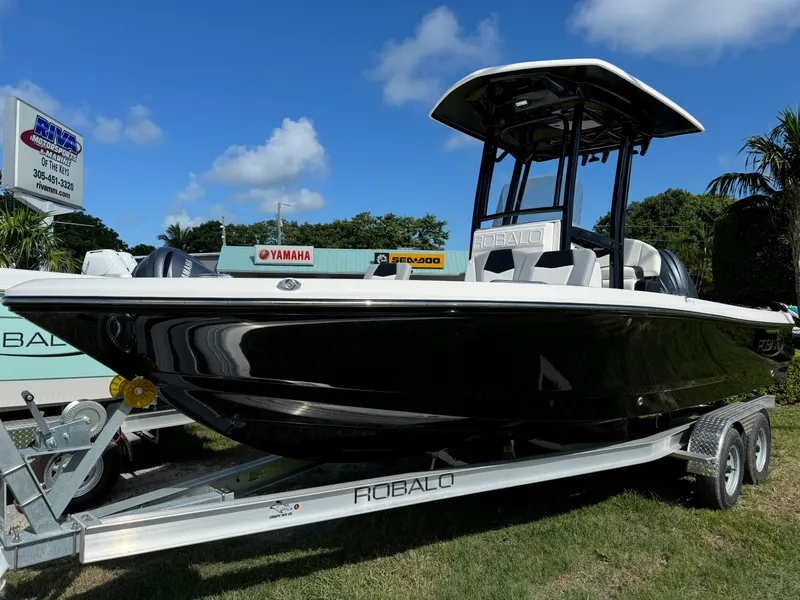 Slide: The Image of 2024 Robalo 226 Cayman boat on trailer, black hull, sunny day. - 1