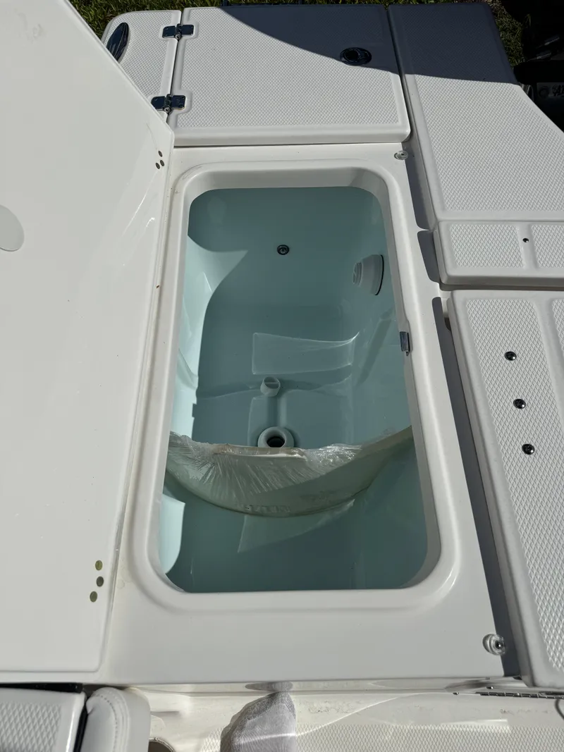 Slide: The Image of 2024 Robalo 226 Cayman boat storage compartment, open lid, white interior. - 11