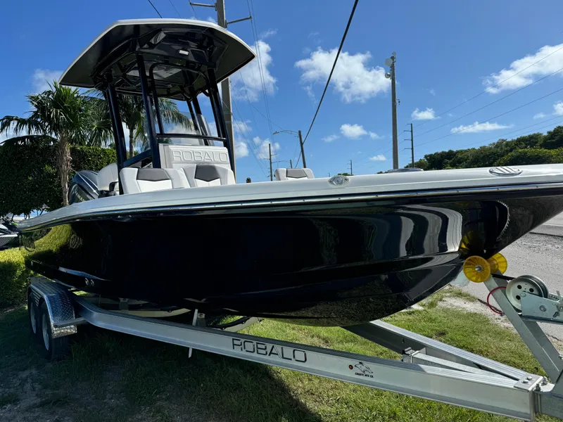 Slide: The Image of 2024 Robalo 226 Cayman boat on trailer, sleek black design, sunny day. - 2