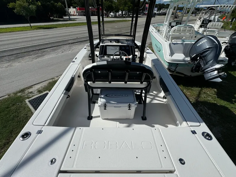 Slide: The Image of 2024 Robalo 226 Cayman boat interior with seating and console, parked outdoors. - 4