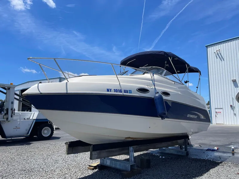 The Image of 2001 Stingray 240 CS boat on a stand under a clear blue sky. - 0
