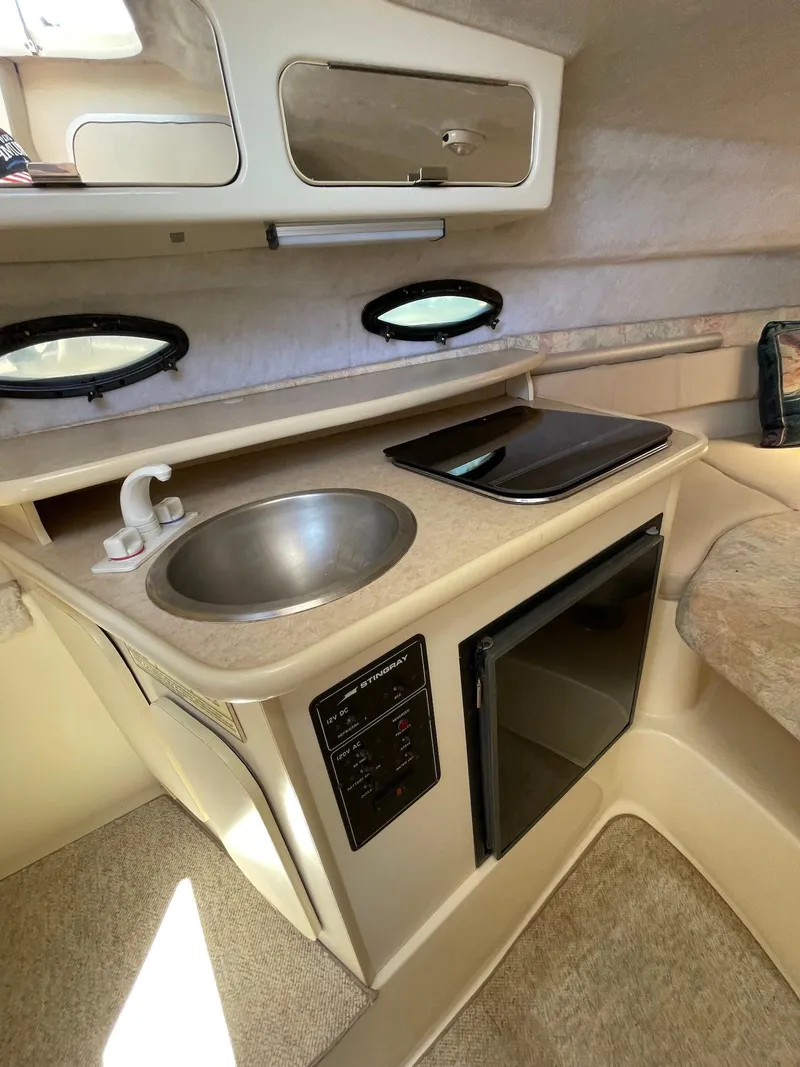 Slide: The Image of 2001 Stingray 240 CS boat interior with kitchenette, sink, stove, and mini-fridge. - 3