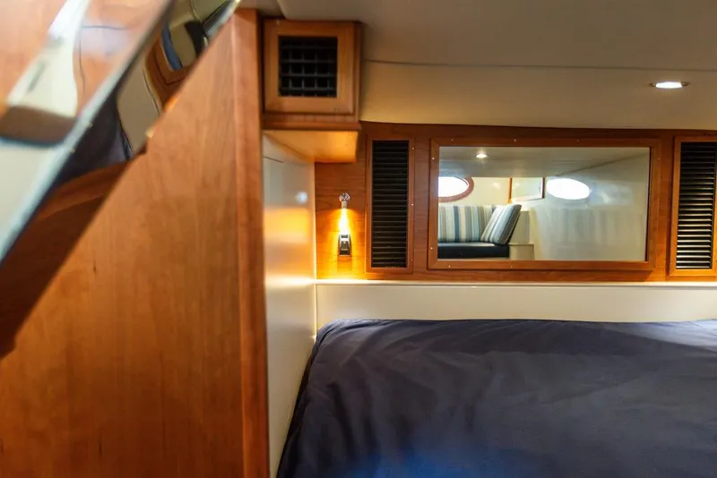 Slide: The Image of 2022 Hinckley Sport Boat 40 X cabin interior with cozy bed and wooden accents. - 46