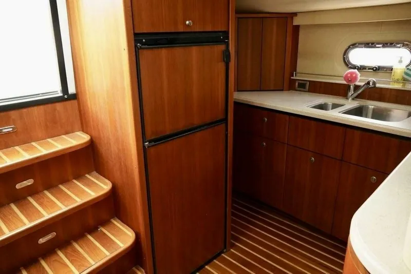 Slide: The Image of 2006 Tiara Yachts 4300 Sovran Express Cruiser kitchen with wooden cabinetry and stairs. - 14