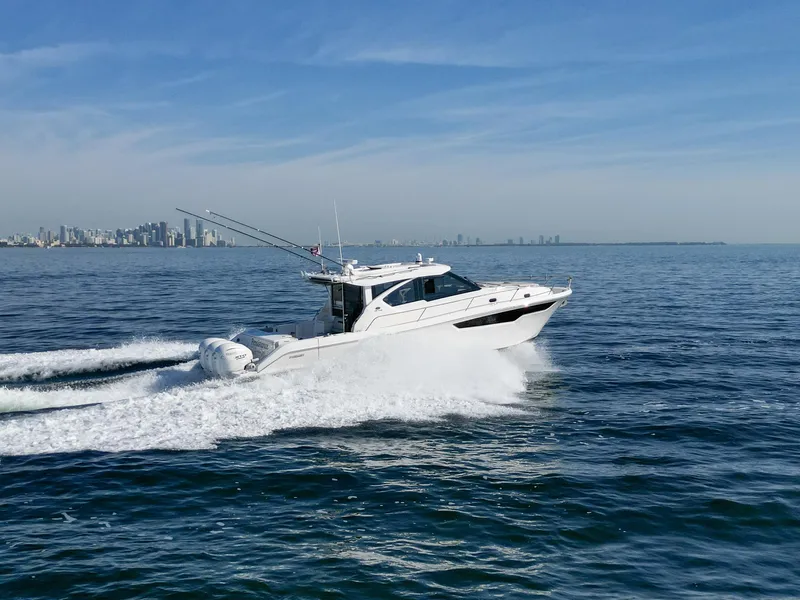 Slide: The Image of 2024 Pursuit OS 445 Offshore boat cruising on open water with city skyline in background. - 11