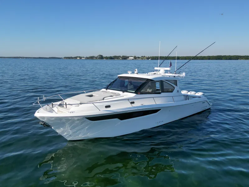 Slide: The Image of 2024 Pursuit OS 445 Offshore boat on calm water under clear blue sky. - 26