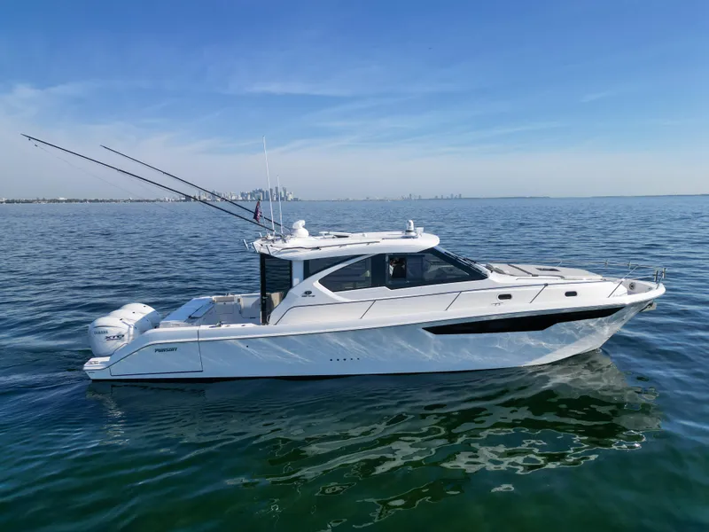 Slide: The Image of 2024 Pursuit OS 445 Offshore boat cruising on calm waters under a clear blue sky. - 29