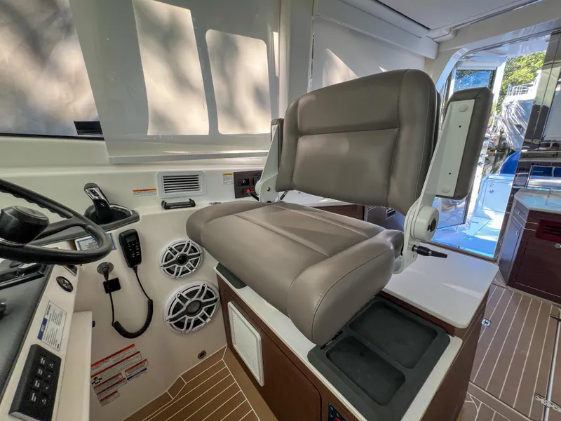 Slide: The Image of Captain's chair in 2024 Pursuit OS 445 Offshore boat cockpit, featuring modern controls and speakers. - 31