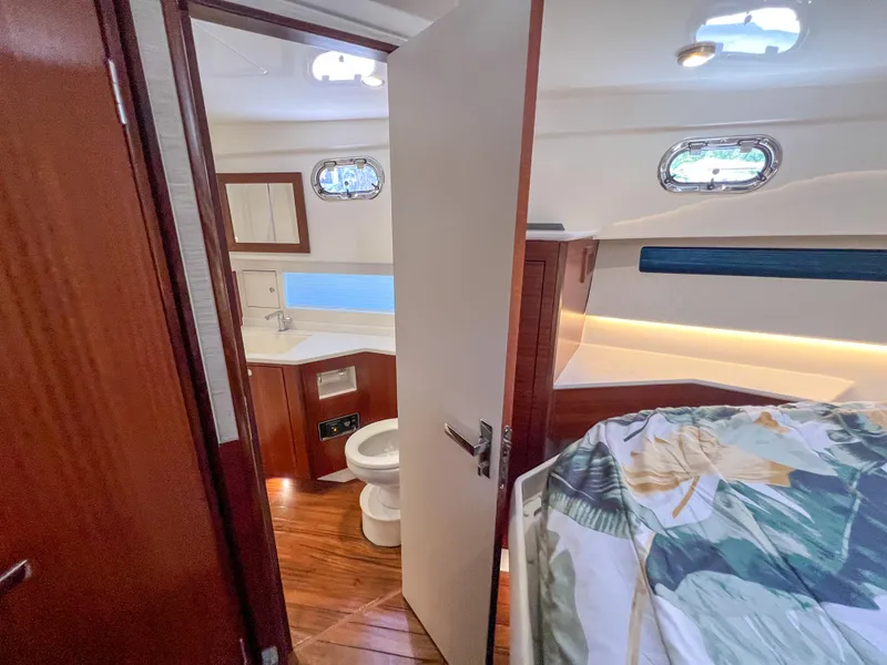 Slide: The Image of 2024 Pursuit OS 445 Offshore cabin interior with bed, bathroom, and wooden flooring. - 39