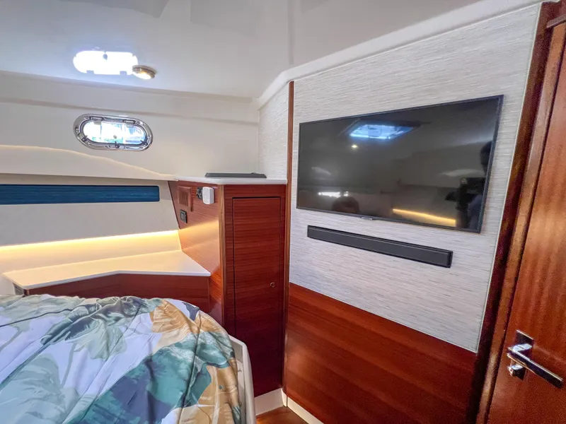 Slide: The Image of 2024 Pursuit OS 445 Offshore cabin interior with TV and wood paneling. - 40
