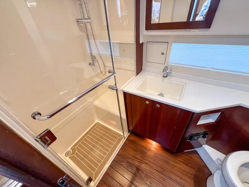 Slide: The Image of 2024 Pursuit OS 445 Offshore bathroom with shower, sink, and wooden flooring. - 43