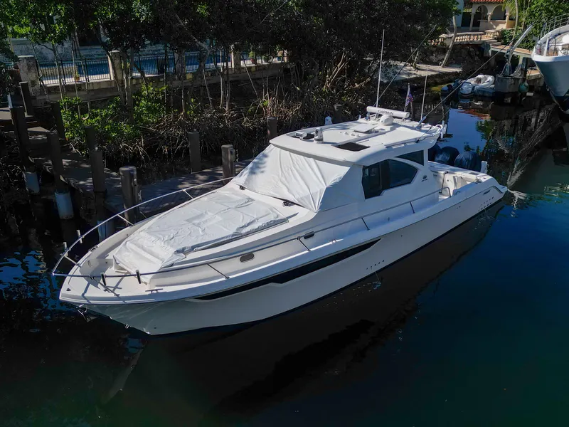 Slide: The Image of 2024 Pursuit OS 445 Offshore boat docked in a serene marina setting. - 7