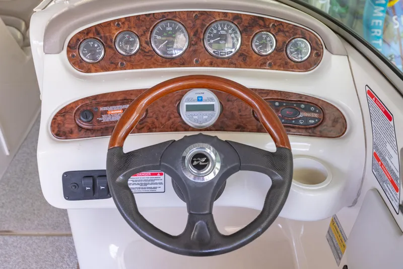 Slide: The Image of 2004 Sea Ray 240 Sundeck dashboard with wood accents and steering wheel. - 13