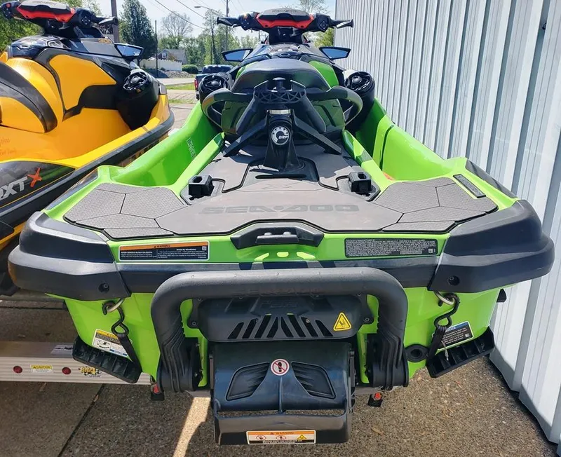 Slide: The Image of 2021 Sea-Doo RXT jet ski in green, rear view, parked next to a yellow jet ski. - 15