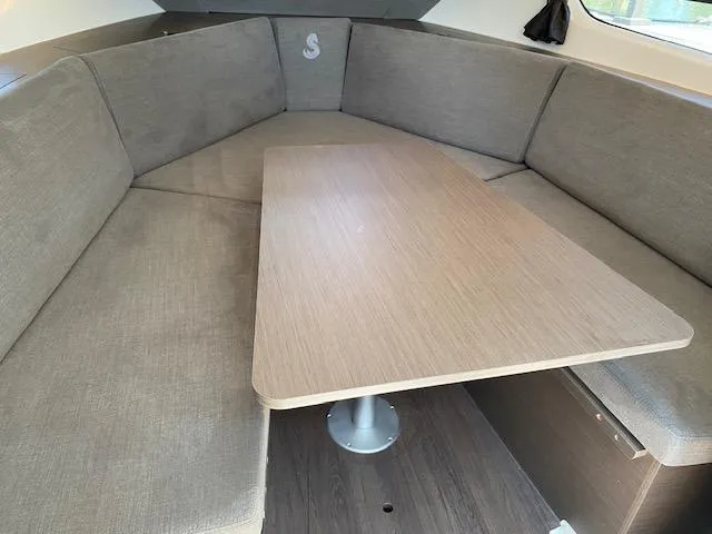 Slide: The Image of 2024 Beneteau Gran Turismo 32 interior with gray seating and wooden table. - 12