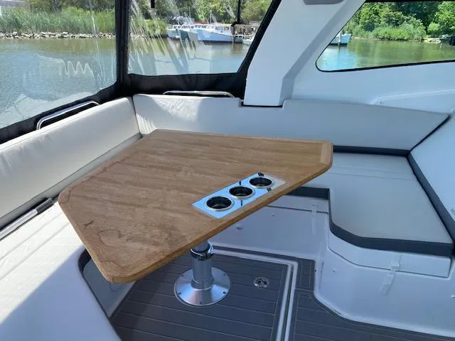 Slide: The Image of 2024 Beneteau Gran Turismo 32 interior with wooden table and seating, overlooking a serene water view. - 8