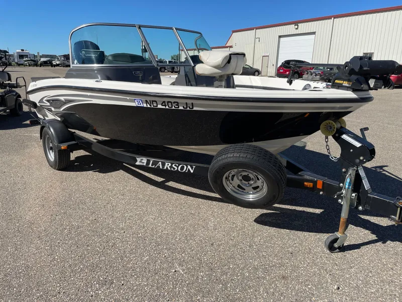 Slide: The Image of 2012 Larson FX 1750 DC boat on a trailer in a parking lot. - 2