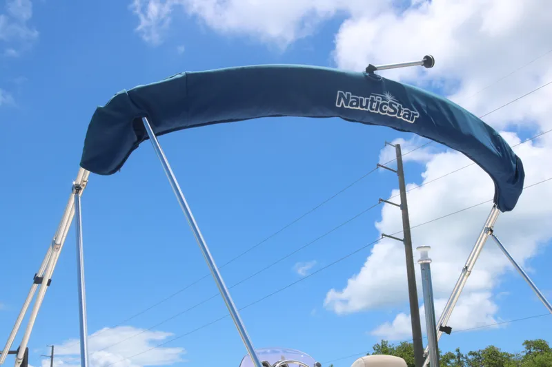 Slide: The Image of 2018 NauticStar 203 SC boat with blue bimini top against a clear sky. - 5