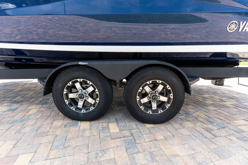 Slide: The Image of 2021 Yamaha Boats 252S trailer with dual wheels on brick pavement. - 13