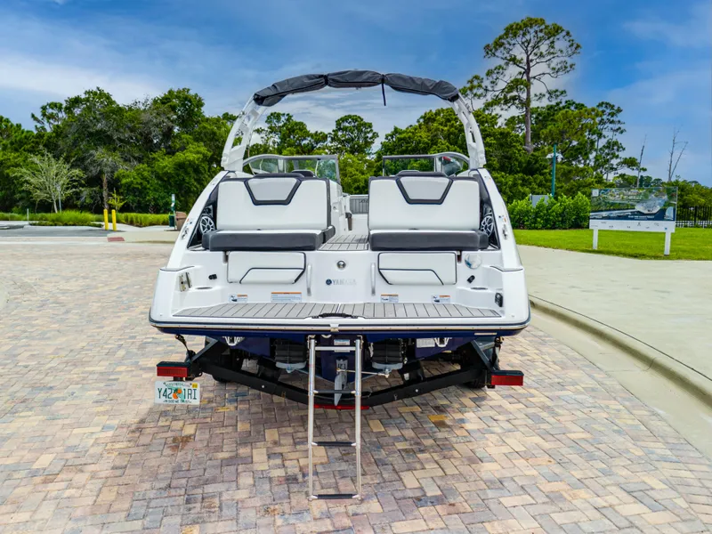 Slide: The Image of 2021 Yamaha Boats 252S with swim platform and ladder, parked on paved area. - 15