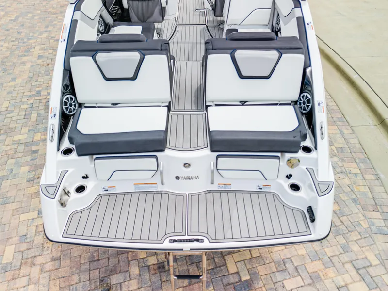 Slide: The Image of 2021 Yamaha Boats 252S interior, featuring sleek seating and modern design on a paved surface. - 16